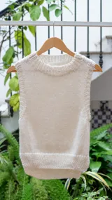 Chaleco tejido color crema, con cuello alto y sin mangas.