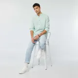 Camisa celeste claro de lino con cuello mao, manga larga con puños abotonados y bolsillo de parche en el pecho.