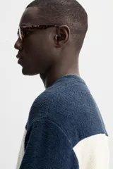 Sudadera de hombre de tejido rizo, corte holgado, con cuello redondo, manga larga y diseño a rayas horizontales en azul marino y blanco.