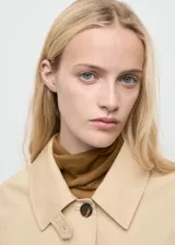 Chaqueta corta de algodón y poliéster color beige, con cuello camisero, cierre frontal de botones y diseño oversize. Posee mangas largas con trabillas ajustables y dos bolsillos laterales.