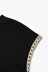 Camiseta negra de cuello redondo y sisa con detalle de fornitura con hilo metalizado a contraste en las mangas.