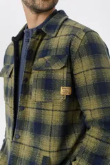 Camisa de franela escocesa con cuello, cierre frontal con botones, dos bolsillos con solapa abotonada en el pecho y corte recto.