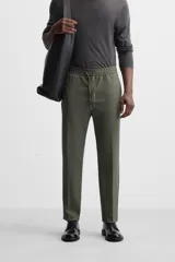 Pantalón color arena de corte recto, confeccionado en tejido elástico. Cuenta con cintura elástica ajustable con cordón, bolsillos laterales y bolsillos de vivo en la parte trasera.