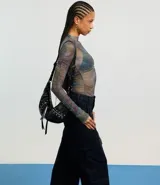 Blusa de tule con cuello alto y mangas largas con fruncido lateral.