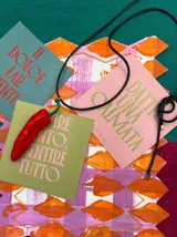 Collar con cordón encerado negro y dije de vidrio artesanal en forma de peperoncino (ají italiano). Largo regulable, sin cierre.