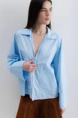 Camisa blanca de algodón con cuello clásico, mangas largas con puños abotonados y bolsillo de parche en el frente.
