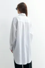 Túnica oversize blanca de manga larga con botones en la parte delantera y corte largo.