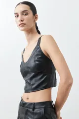Top negro de eco cuero con corte crop, breteles finos y detalle de tul en el escote.