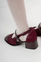 Zapato tipo ballerina color borgoña, con puntera charolada, hebilla lateral y taco cuadrado.