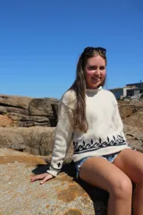 Sweater tejido a mano en lana merino color crema con diseño geométrico en negro en el pecho y puños.