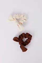 Set de dos scrunchies para el pelo, uno color beige y otro color marrón, con moño.