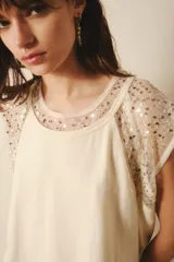 Remera negra de jersey de algodón grueso, corte ancho y mangas cortas. Cuello y mangas confeccionados en microtul bordado con lentejuelas.