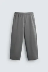 Pantalón jogger negro de corte ancho, confeccionado en tejido de algodón con interior de rizo. Cuenta con cintura elástica ajustable con cordón interior, bolsillos laterales y bolsillo trasero de parche.