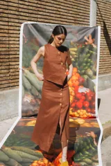 Falda marrón de corte midi con abertura frontal y botones dorados.