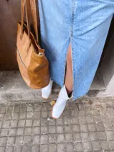 Bolso tipo tote de cuero color camel con paneles laterales texturizados. Tiene doble asa de hombro, cierre superior con cremallera y bolsillos internos.