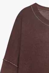 Sweater gris de punto con cuello redondo y manga larga. Detalle de costuras a contraste en color blanco en cuello y hombros.