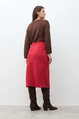 Falda midi de simil gamuza color rojo intenso, con tajo frontal central y paneles cosidos que le dan estructura.