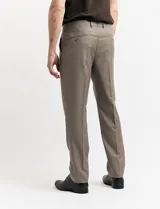 Traje de vestir color marrón topo, compuesto por saco de dos botones con solapa de muesca, dos bolsillos delanteros con solapa y un bolsillo superior. Pantalón de vestir con corte recto y bolsillos laterales. Incluye camisa blanca y corbata azul con lunares blancos.