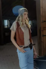 Chaleco de cuero marrón con detalle de tachas en el contorno.