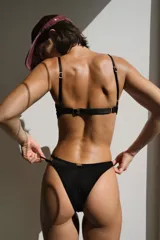 Bottom de bikini negro, corte vedetina angosta con argolla de resina decorativa.