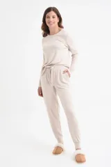 Conjunto de pantalón y remera de mangas largas color beige, de corte holgado. El pantalón tiene cintura elástica con cordón ajustable y bolsillos laterales.