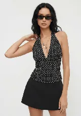 Top halter negro con lunares blancos, escote en V pronunciado y espalda descubierta.