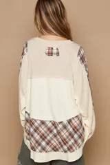 Blusa oversize estilo patchwork, con combinación de paneles lisos y a cuadros. Mangas largas holgadas con puños y tapeta con botones metálicos.