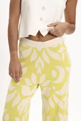 Pantalón palazzo de tejido de punto color amarillo con estampado de hojas blancas.