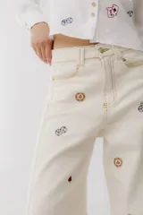 Pantalón de jean color crudo, corte wide leg, con bordados de cartas, dados y fichas de casino.
