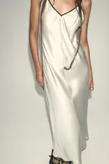 Vestido largo color blanco hueso de satén, con escote en V y tirantes finos negros ajustables en la espalda.