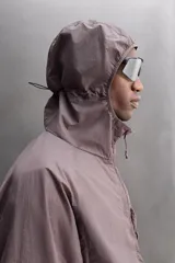 Cazadora marrón de tejido técnico ligero con partículas reflectantes. Tiene cuello alto con capucha elástica, mangas largas con puños elásticos, bolsillos frontales con cremallera en pecho y cadera, y cierre frontal con cremallera. Pertenece a la línea Zara Athleticz.