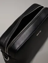 Bandolera negra Calvin Klein Must de piel sintética granulada, con correa ajustable jacquard con logo, cierre de cremallera, bolsillo interior y logo de metal plateado brillante en la parte delantera.