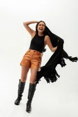 Ruana de tejido de punto color negro, confeccionada en lana merino. Presenta un diseño abierto con terminación de flecos en el ruedo.