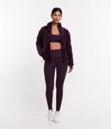 Campera deportiva de terciopelo color violeta, con cuello alto, cierre de botones, bolsillos laterales y puños ajustados.