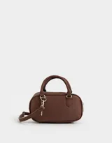 Cartera bowling color marrón chocolate, de cuero sintético, con doble asa corta, correa larga regulable y desmontable, y charm colgante.