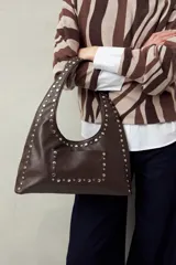Cartera negra tipo hobo de cuero sintético con apliques de tachas metálicas plateadas en el frente y los bordes.