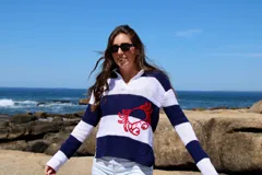 Sweater tejido de hilo de algodón a rayas horizontales blancas y azul marino, con cuello polo y bordado de un cangrejo rojo en el frente.