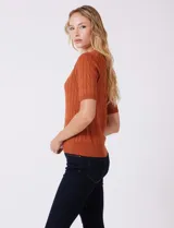 Buzo de punto marca Tahari con diseño de ochos verticales, cuello a la base y manga corta en color marrón.