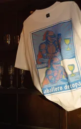 Remera blanca de algodón con cuello redondo y calce oversize. Estampado con diseño de dos caballeros medievales con armadura y capa roja, uno usando un celular y otro con una copa.