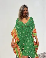 Túnica corta verde con estampado de flores blancas y detalles bordados en el escote. Mangas anchas con terminación en tela estampada a rayas naranjas y blancas.