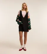 Vestido corto negro de poliéster, con breteles anchos, escote V delantero y trasero y bolsillos grandes.