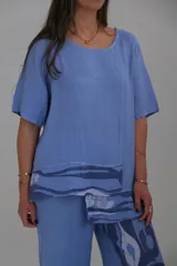 Blusa celeste de lino con mangas cortas y estampado abstracto en el ruedo.