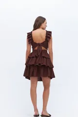 Falda corta de lino color rosado, con cintura marcada y tres volados superpuestos que generan volumen.