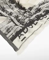 Chal de algodón orgánico con estampado a cuadros en blanco y negro, con efecto pincelada y bordes desflecados. Presenta el logo estampado en la parte inferior.