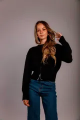 Buzo gris de punto con cuello redondo, mangas largas abullonadas y cierre frontal asimétrico.