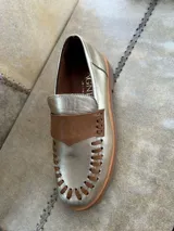 Mocasín color dorado suave con aplique marrón en el empeine y detalle de costuras en el borde.