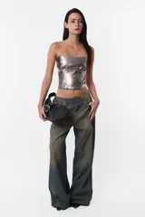 Corset strapless plateado de cuerina PU con cinto en la espalda con hebilla y ojalillos metálicos para ajuste y cierre metálico para acceso a la prenda. Detalle de recortes en delantero y espalda que simulan ballenas.