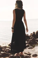 Vestido midi negro de lino con escote cuadrado, sin mangas, con botones dorados en el frente y abertura en el ruedo.