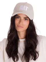 Gorro de béisbol color beige claro, confeccionado en sarga de algodón teñida con pigmentos. Presenta visera curva y el logo de Caterpillar (CAT) bordado en blanco en el panel frontal. Posee ajuste trasero con broche metálico.