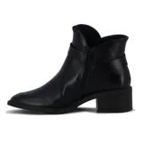 Bota de cuero negra de caña baja, con taco cuadrado y punta fina. Presenta una correa con hebilla alrededor del tobillo y un aplique metálico en el lateral. Cuenta con cierre lateral.